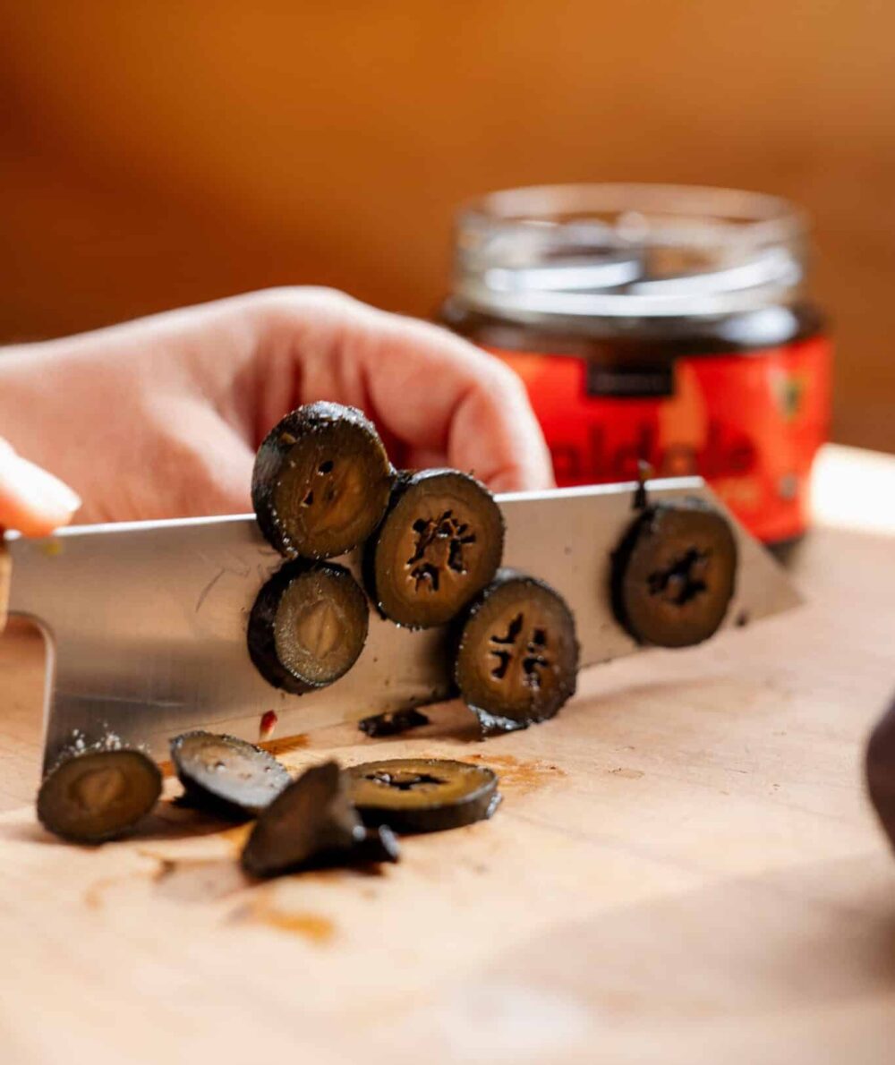A knife slicing through a pickled walnut.