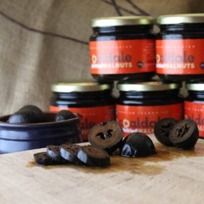 Sliced pickled walnuts with red-labelled jars in the background