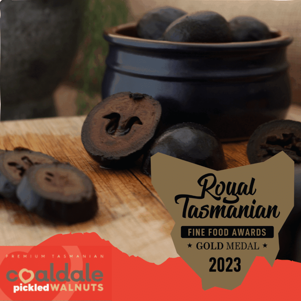 A dish of black-coloured pickled walnuts with the Royal Tasmanian Fine Food Awards 2023 gold meal logo.