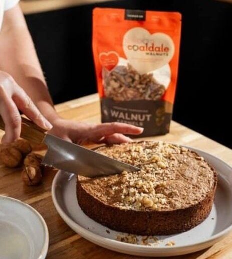 Cutting a cake with walnut pouch next to it